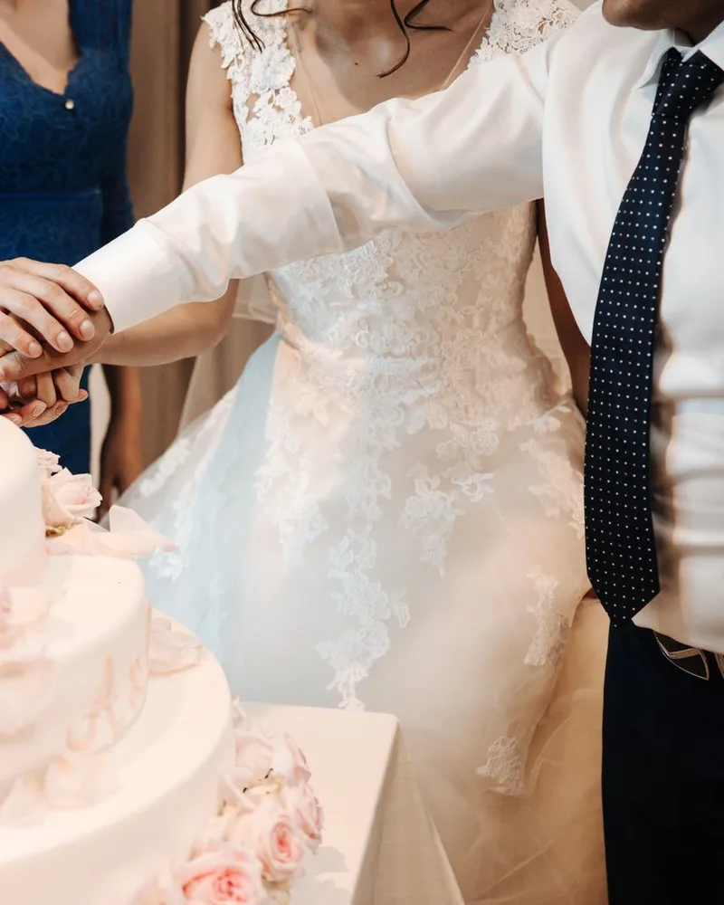 The couple cutting a white rose cake together