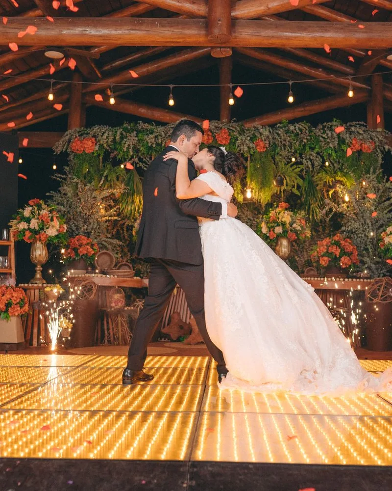The couple kissing on a glowing dance floor under flowers