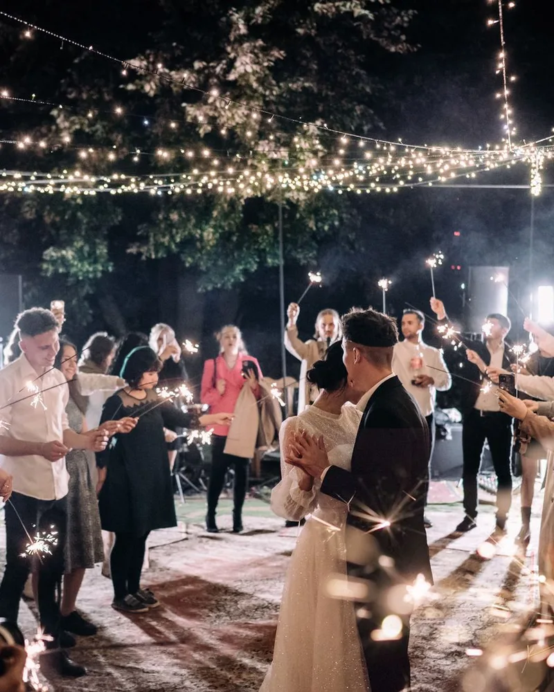 Guests holding sparklers around the couple at night